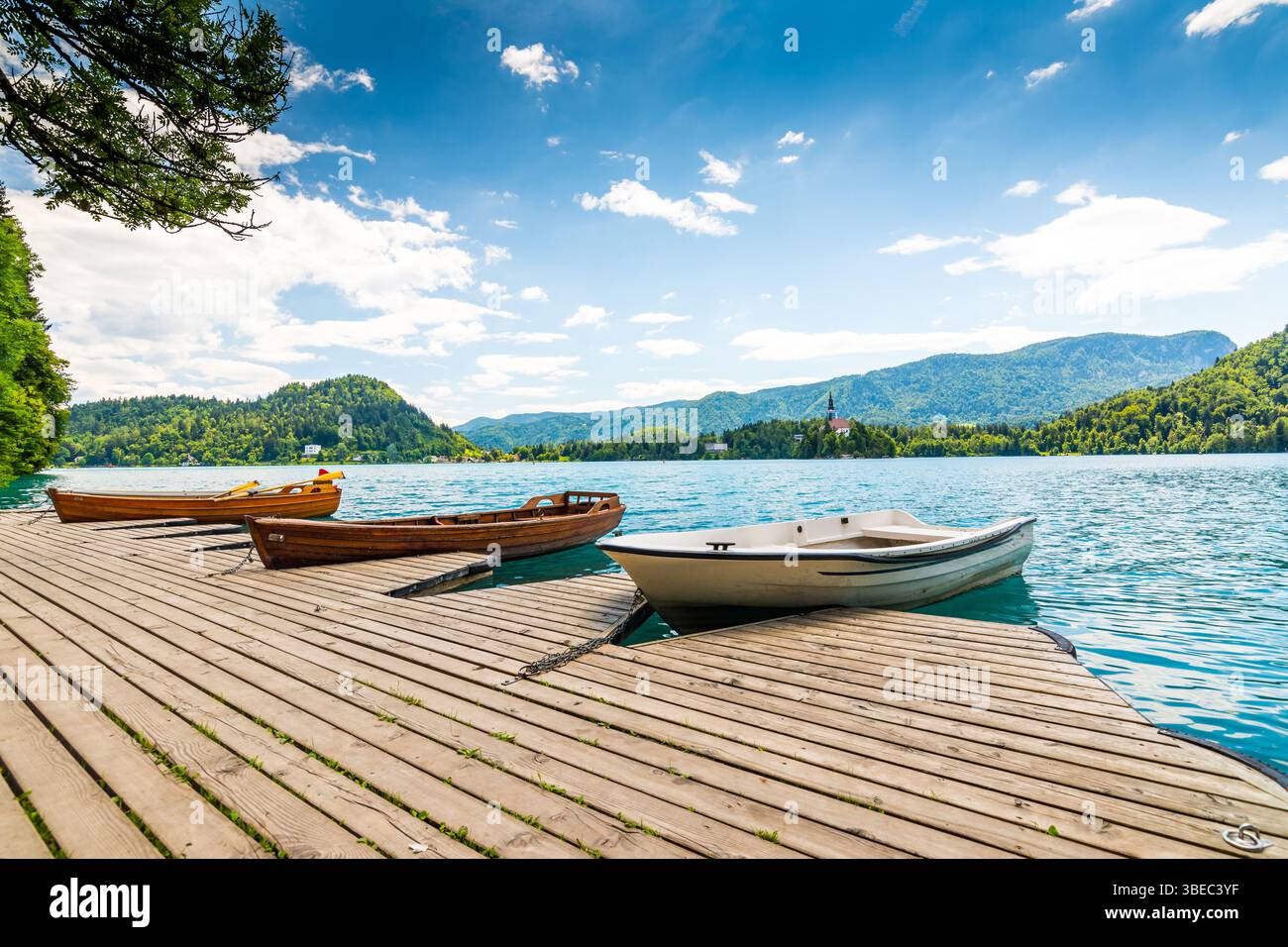 Hafen und Boot auf dem Bleder See, Slowenien. Holzboote auf dem reinen blauen Wasser. Sommertag in der Nähe der Alpen und des Waldes. Stockfoto