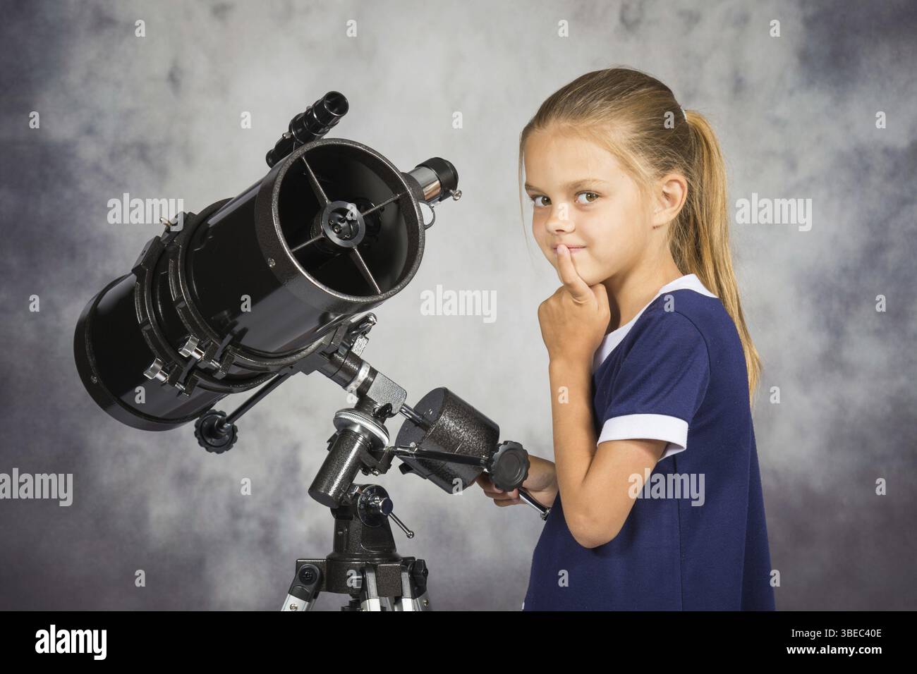 Siebenjährige Mädchen schaut nachdenklich auf dem Bild, stehend am Teleskop Stockfoto