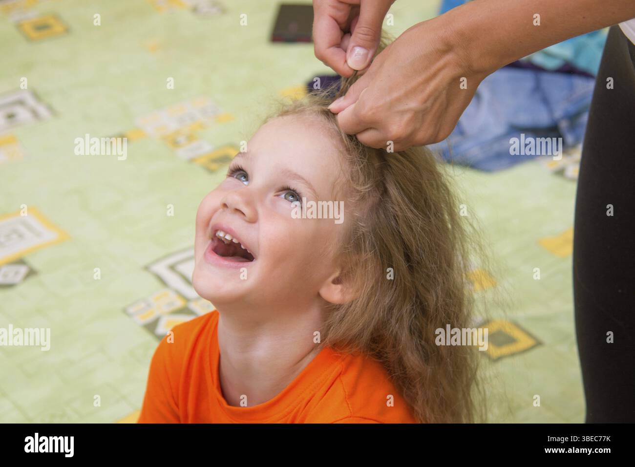 Ein Mädchen von vier Jahren sitzen und lachen gerne, wenn sie ihr Haar gemacht Stockfoto