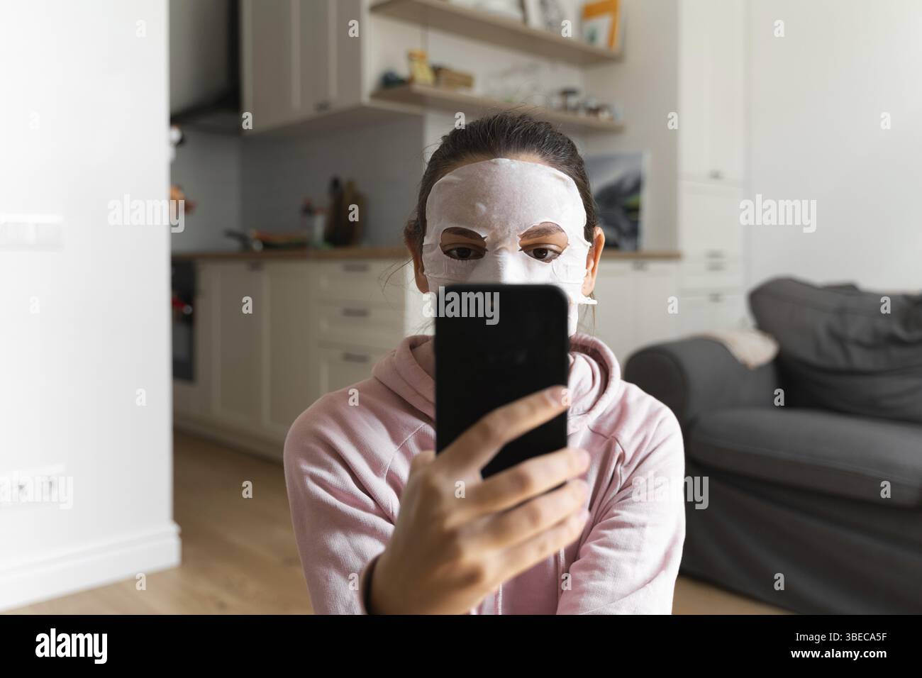 Junge Frau mit Schönheitsmaske zu Hause. Wellness-Konzept. Entspannung zu Hause für junge Mutter. Schnelle Gesichtsmaske für Home Spa. Stockfoto