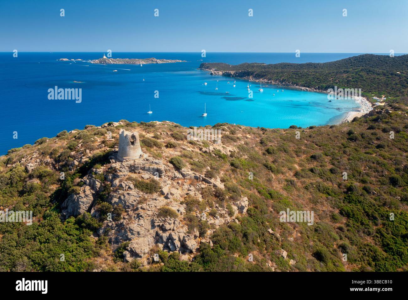 Aus der Vogelperspektive auf den wunderschönen Sandstrand, den alten Turm auf dem Hügel, die Meeresbucht, die Berge am sonnigen Sommertag. Porto Giunco in Sardinien, Italien. Draufsicht von Blau Stockfoto
