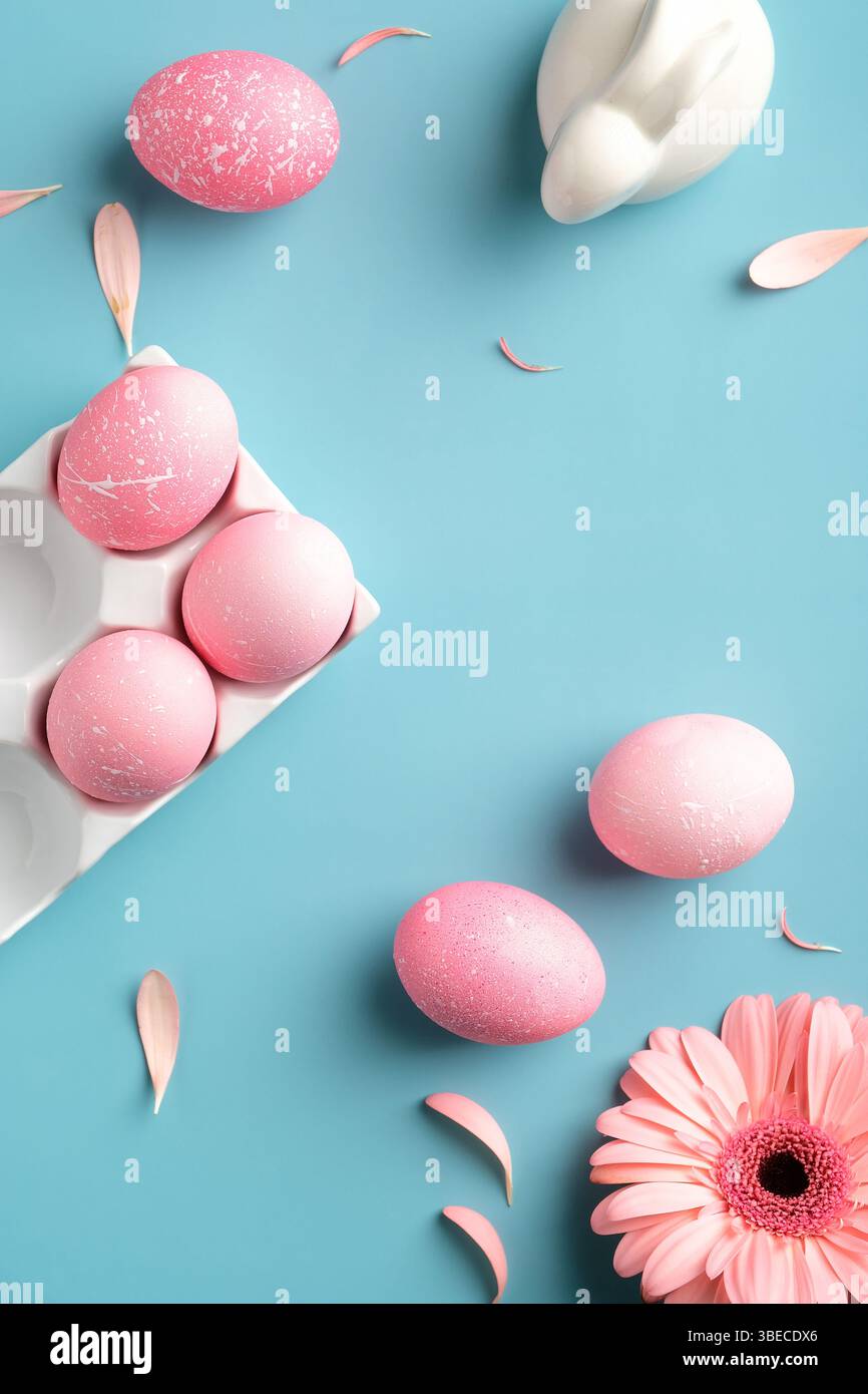 Rosa Ostereier, Hase Kaninchen, Frühlingsblumen auf türkisfarbenem Hintergrund. Blick von oben, flach liegend. Vertikales Banner für Social-Media-Geschichten. Stockfoto