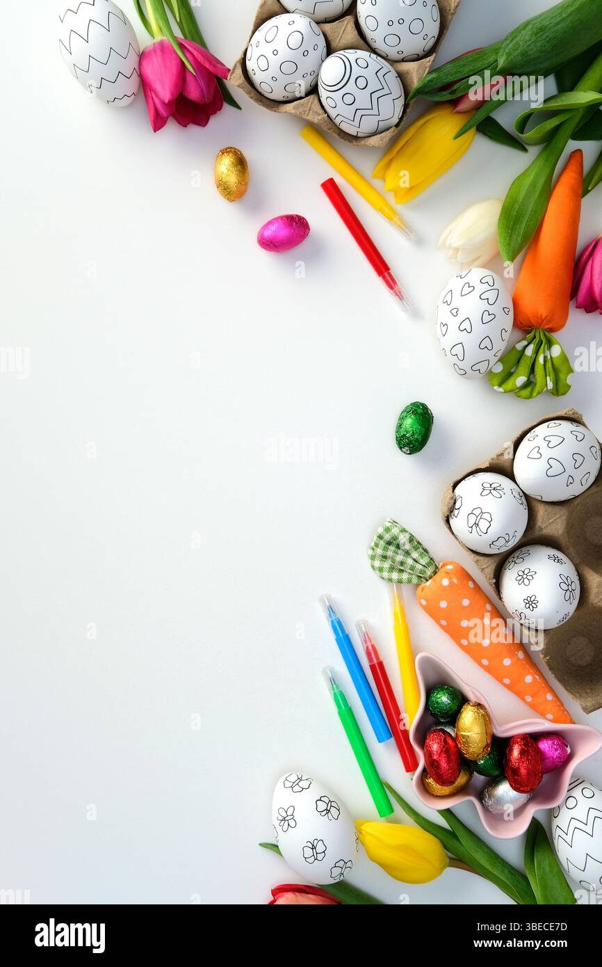 Ostereier zum Färben, Filzstifte, Tulpen und festliche Dekorationen auf weißem Hintergrund. Flache Lage, Draufsicht. Stockfoto