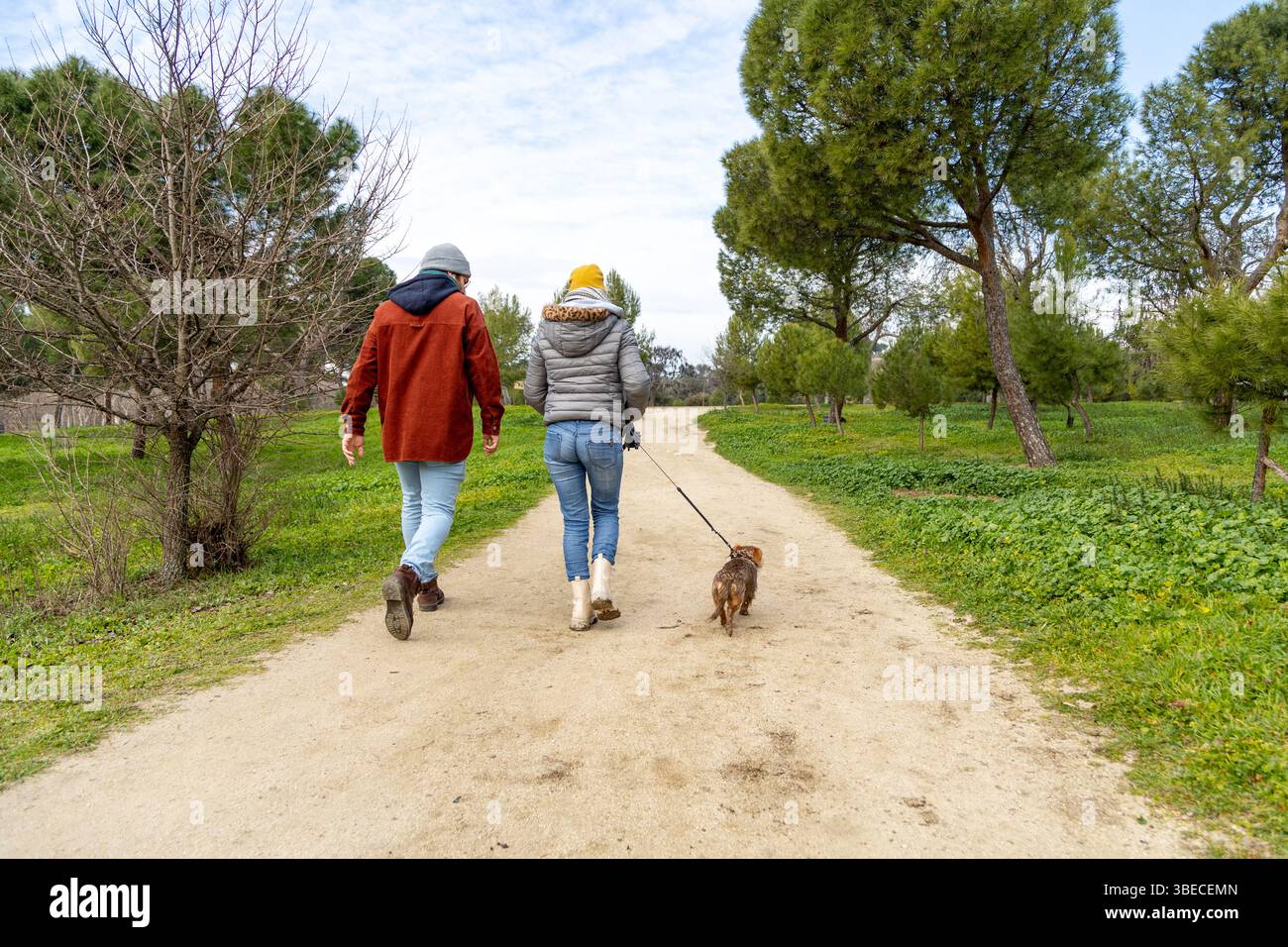 Paare genießen einen gemütlichen Spaziergang mit ihrem Dackel an einem sonnigen Tag und genießen die Ruhe der Natur Stockfoto