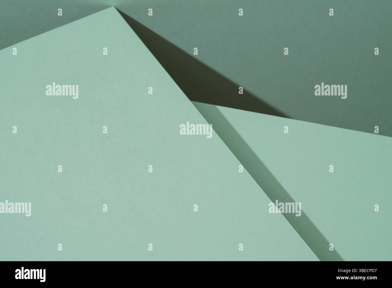 Der farbenfrohe Hintergrund aus grünem Papier mit Schatten. Abstrakte Geometrie Stockfoto