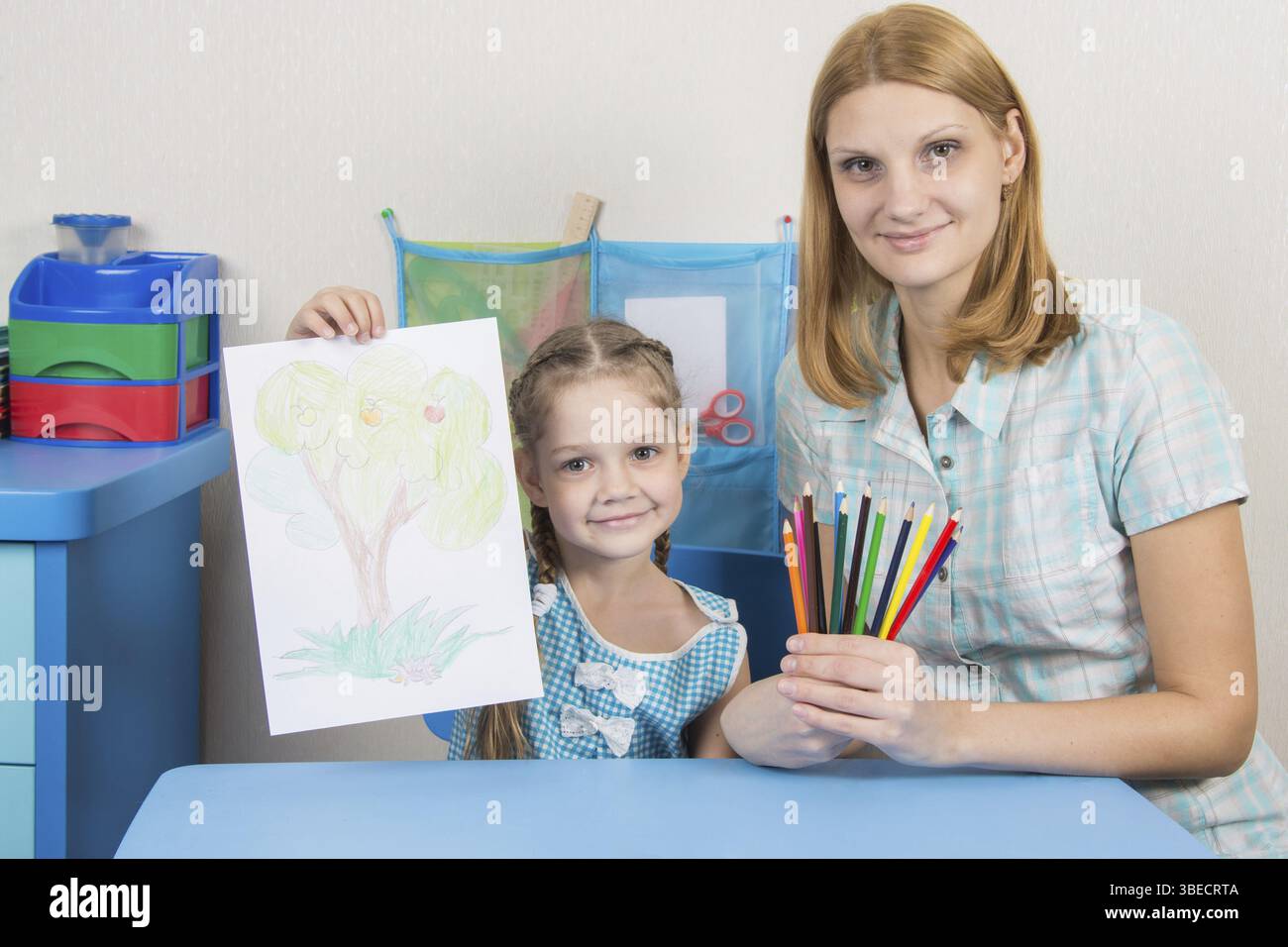 Eine fünfjähriges Mädchen engagiert sich Erwachsene junge schöne Mädchen sitzen am Tisch zu Hause Kinder Stockfoto