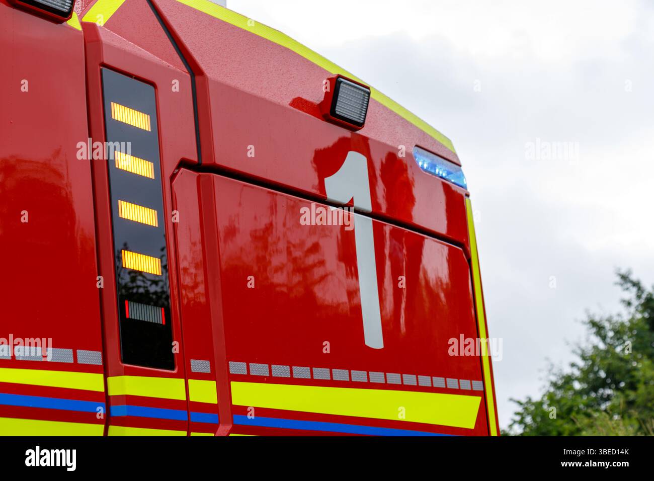 Nürnberg, Deutschland - 25. Mai 2025: Nahaufnahme der Seite eines roten Feuerwehrwagens mit gelben und blauen Streifen, mit weißer Nummer „1“ und diversen li Stockfoto