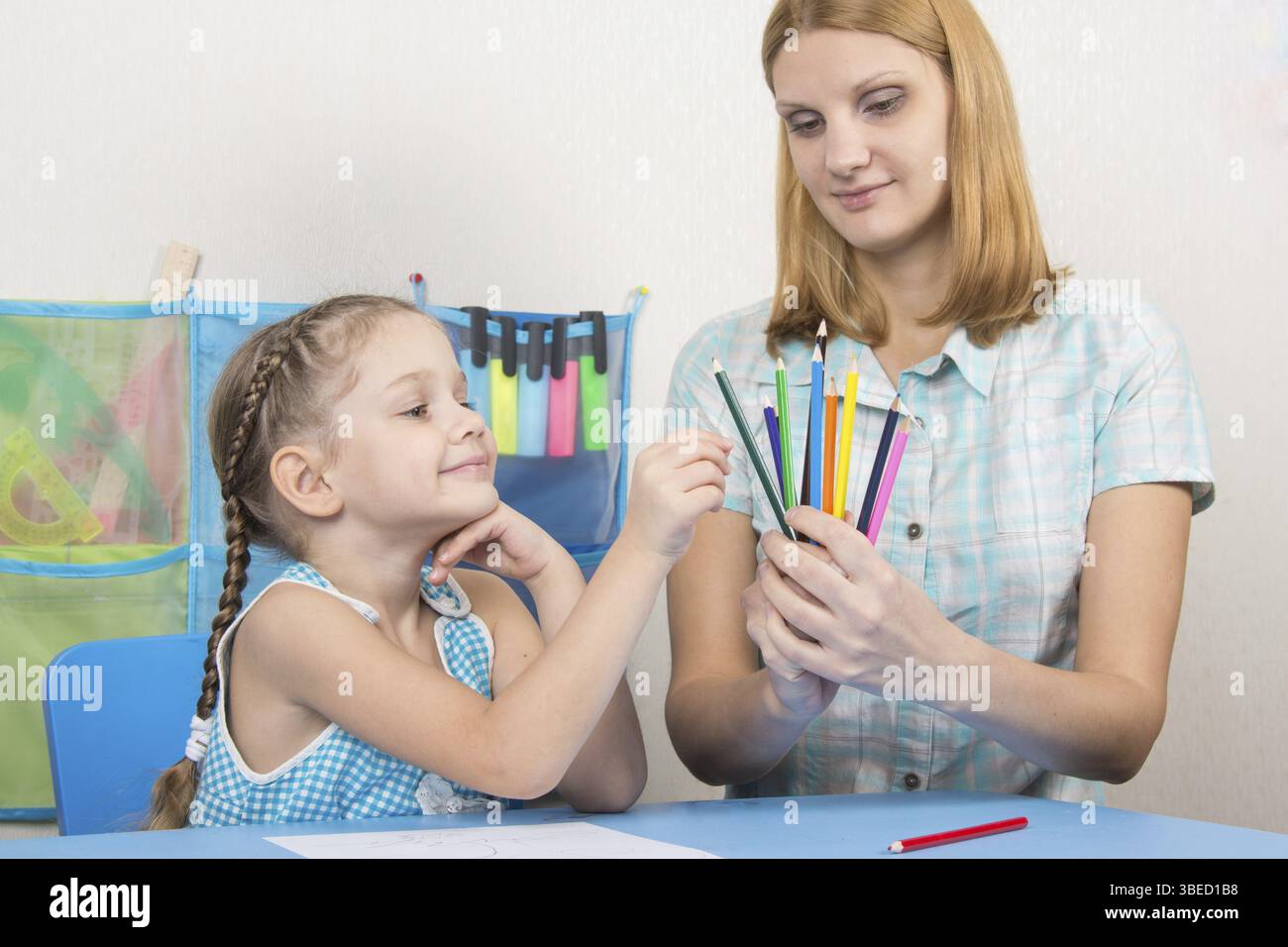 Eine fünfjähriges Mädchen engagiert sich Erwachsene junge schöne Mädchen sitzen am Tisch zu Hause Kinder Stockfoto