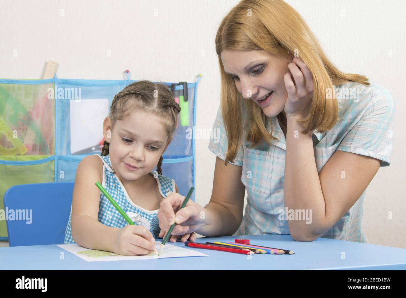 Eine fünfjähriges Mädchen engagiert sich Erwachsene junge schöne Mädchen sitzen am Tisch zu Hause Kinder Stockfoto