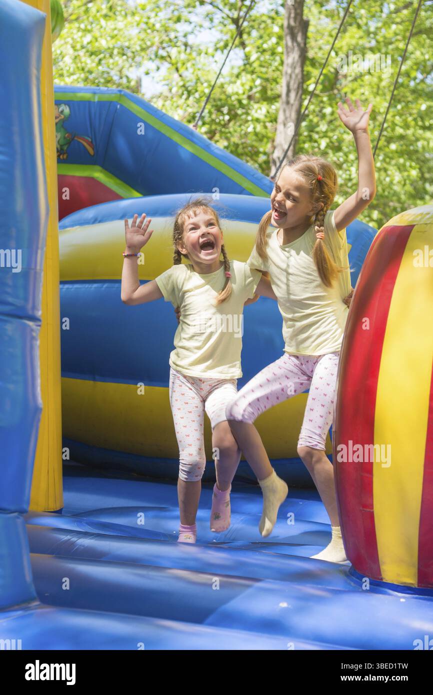 Zwei Mädchen verzog das Gesicht glücklich auf einem aufblasbaren Trampolin springen Stockfoto