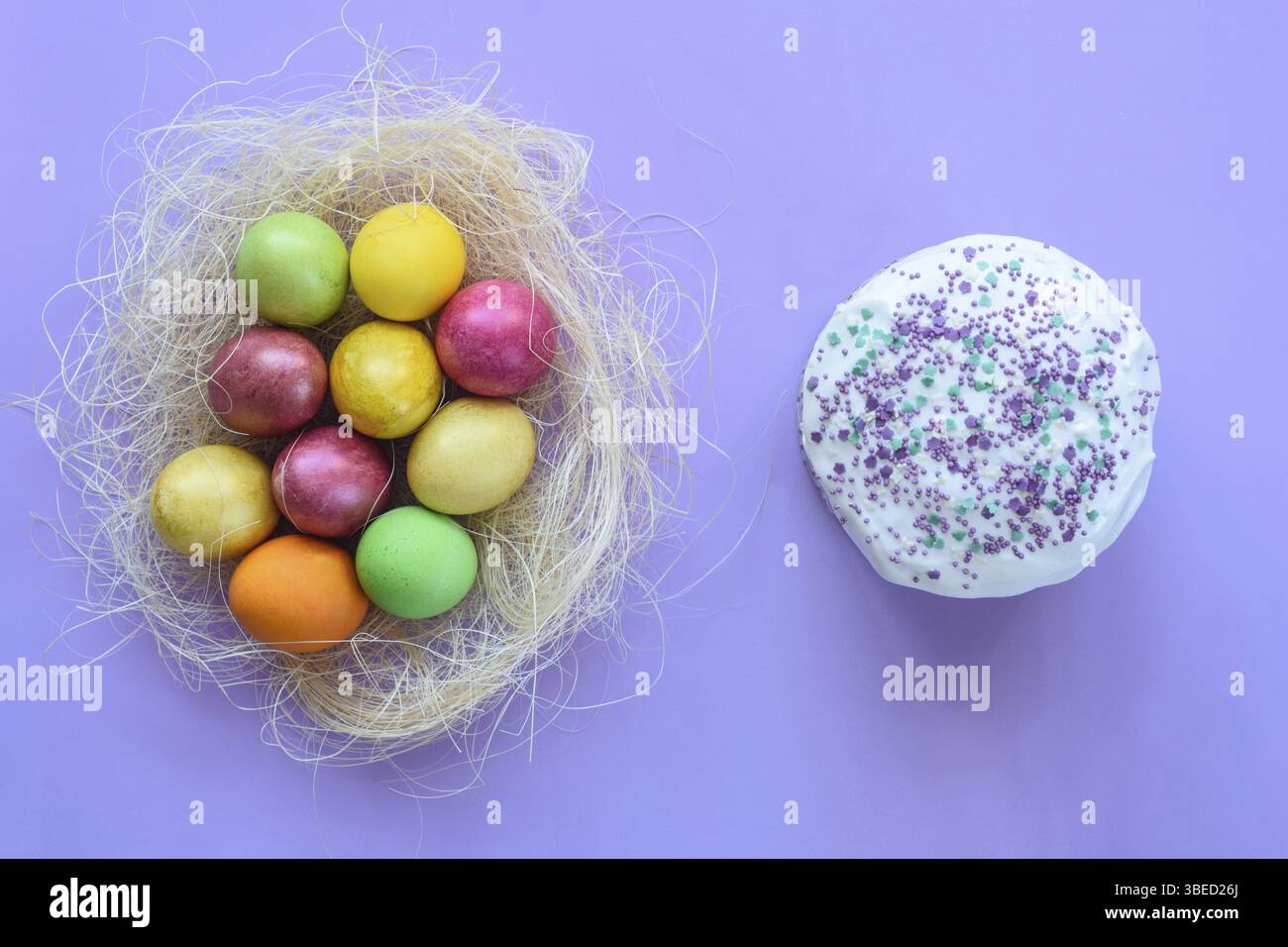 Ostereier in einem provisorischen Nest auf violettem Hintergrund, neben dem Osterkuchen Stockfoto
