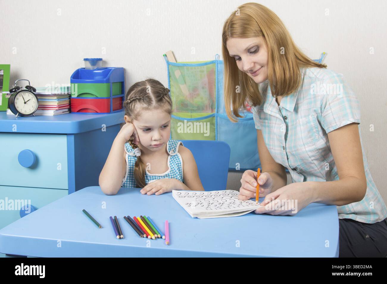 Eine fünfjähriges Mädchen engagiert sich Erwachsene junge schöne Mädchen sitzen am Tisch zu Hause Kinder Stockfoto