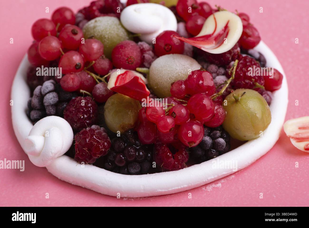 Eine Nahaufnahme eines leckeren rosafarbenen Beerenmousse-Kuchens, dekoriert mit einigen Beeren Stockfoto