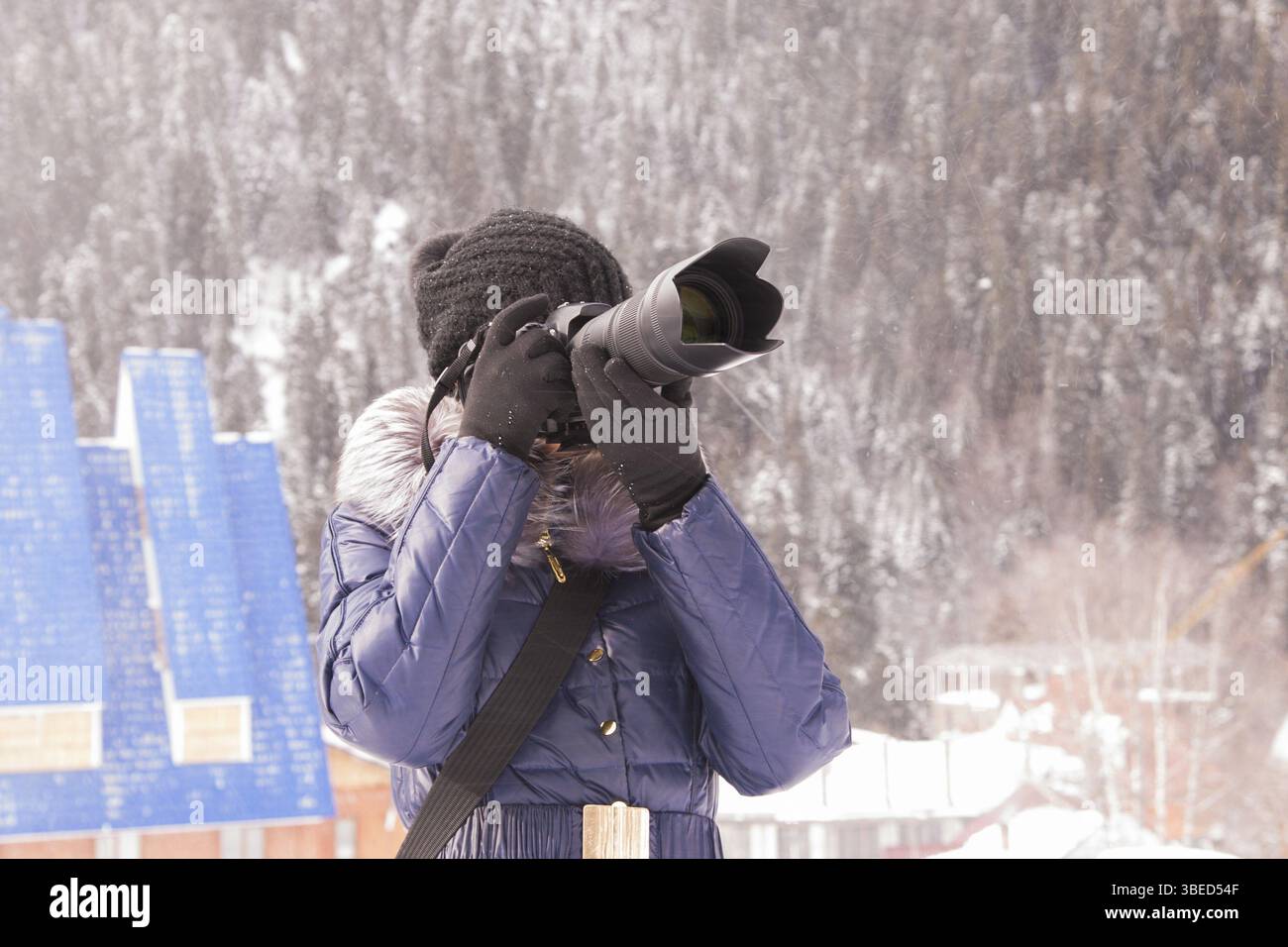 Ein junges Mädchen nimmt Bilder Winter Berglandschaft in einem Schneesturm auf eine SLR-Kamera mit Teleobjektiv Stockfoto