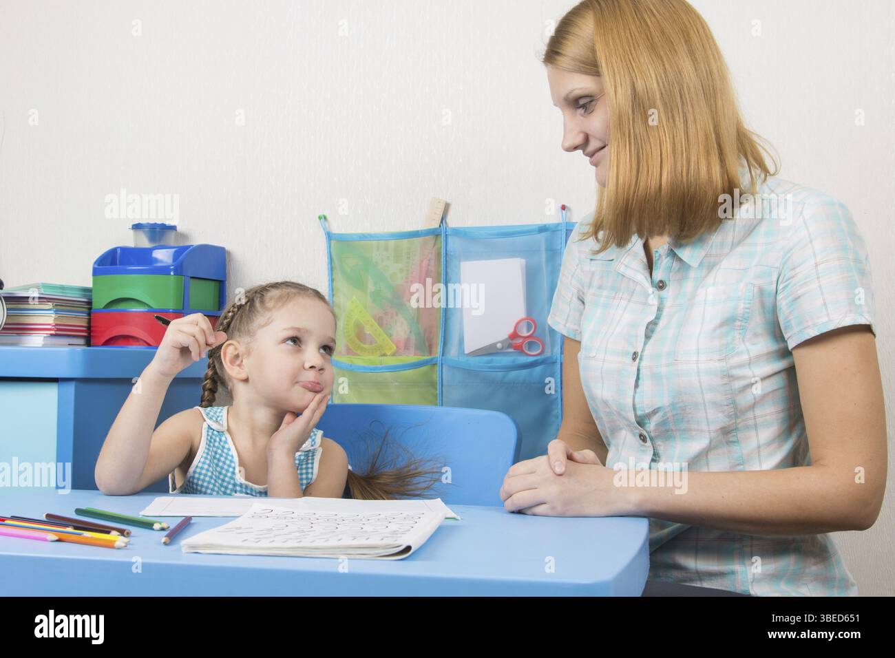Eine fünfjähriges Mädchen engagiert sich Erwachsene junge schöne Mädchen sitzen am Tisch zu Hause Kinder Stockfoto