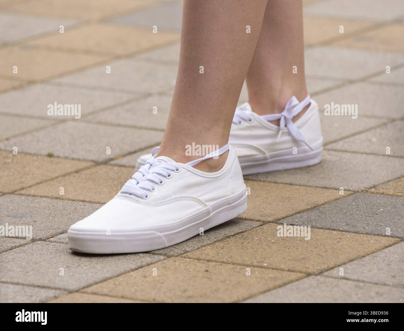 Weibliche sneakers sind auf einem Mädchen gekleidet, ein Mädchen auf dem Bürgersteig steht. Stockfoto