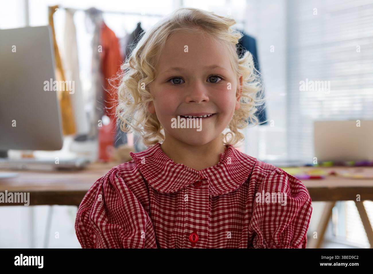Mädchen, das im Studio vor dem Schreibtisch steht, mit Bastelbedarf und Kleiderständer Stockfoto