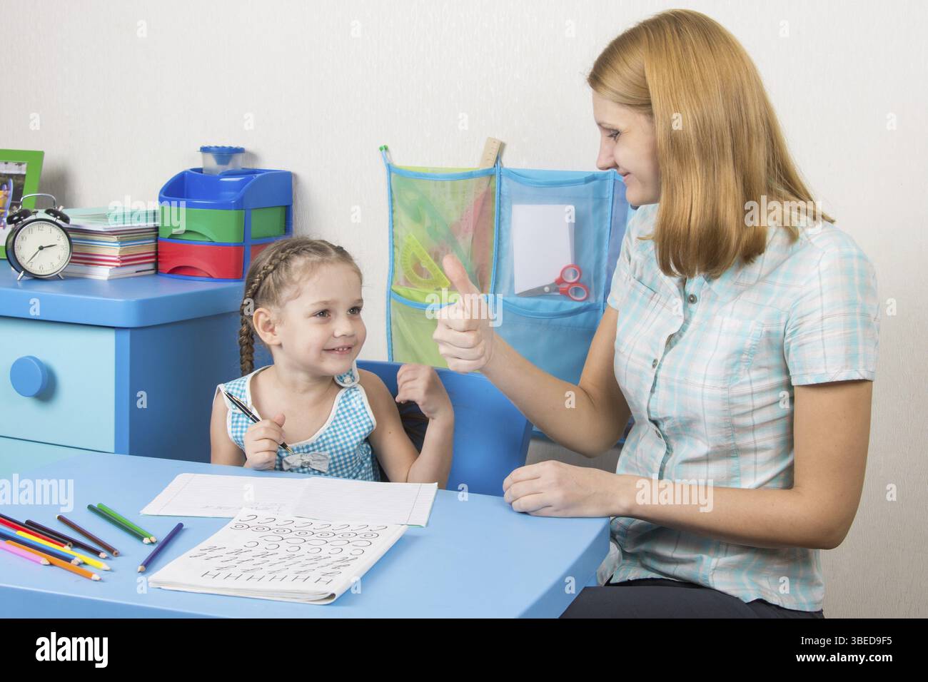 Eine fünfjähriges Mädchen engagiert sich Erwachsene junge schöne Mädchen sitzen am Tisch zu Hause Kinder Stockfoto