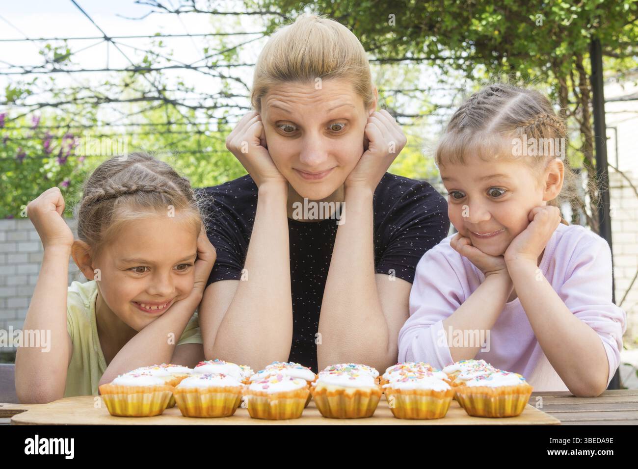 Mutter und zwei Töchter mit einen guten Appetit und großen Augen Blick auf Ostern cupcakes Stockfoto