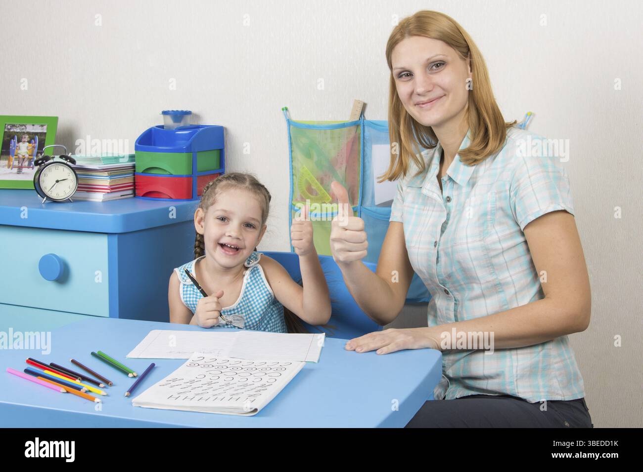 Eine fünfjähriges Mädchen engagiert sich Erwachsene junge schöne Mädchen sitzen am Tisch zu Hause Kinder Stockfoto
