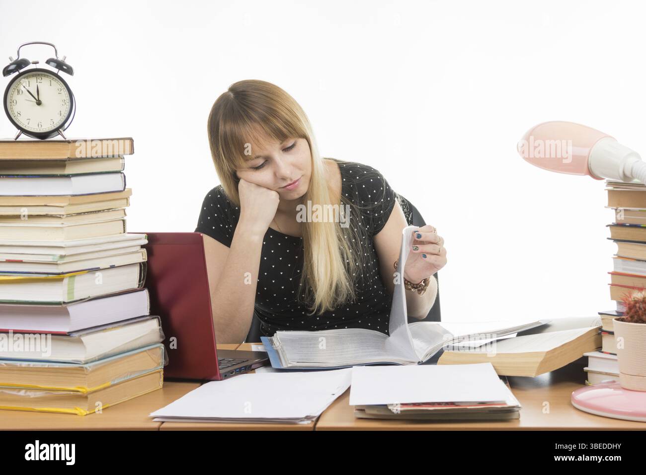 Schüler betrachten leider blätterte in einem Ordner auf dem Schreibtisch unter den Stapel von Büchern Stockfoto
