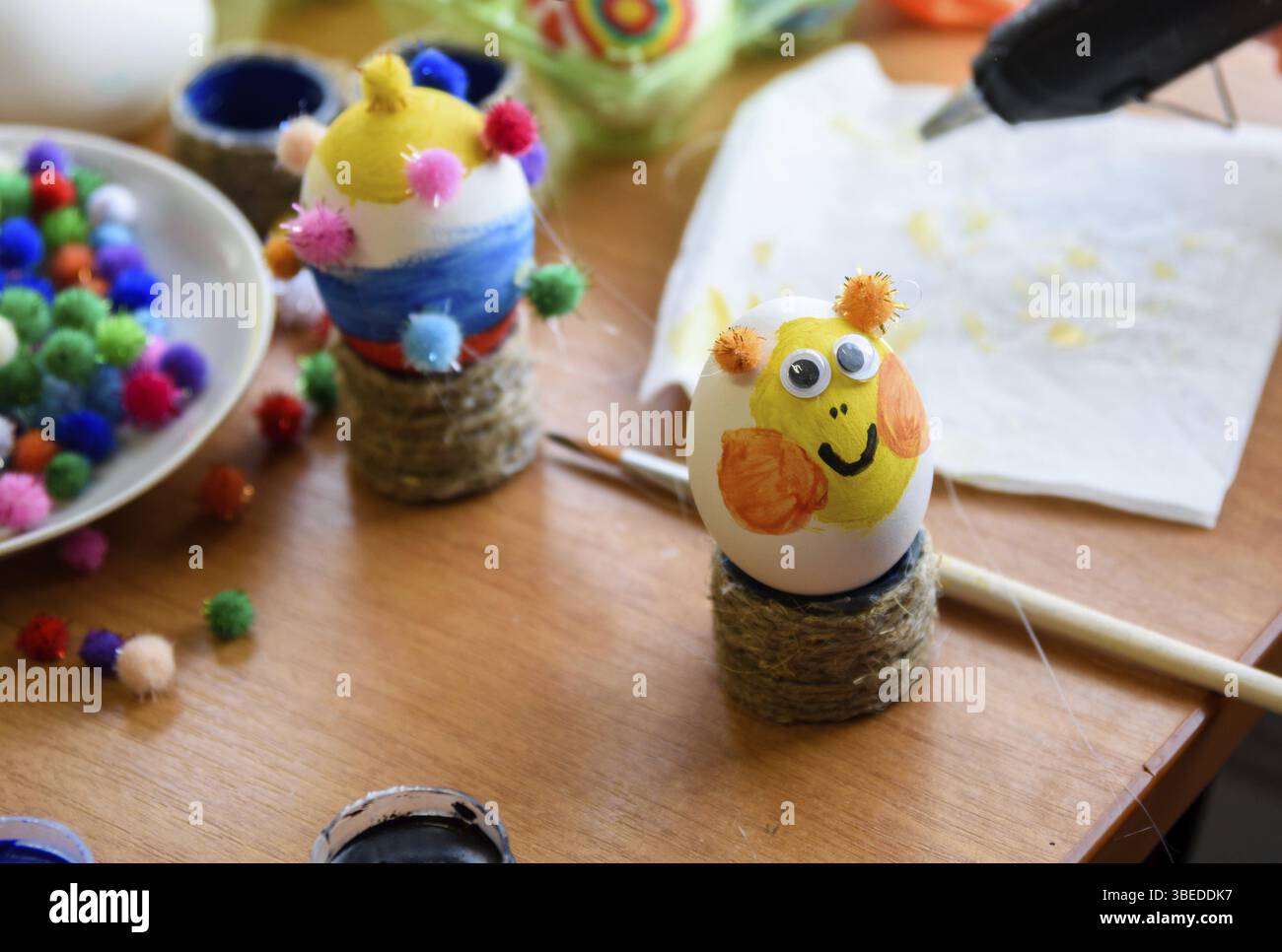 Bemaltes osterei mit geklebten Augen steht auf dem Tisch Stockfoto