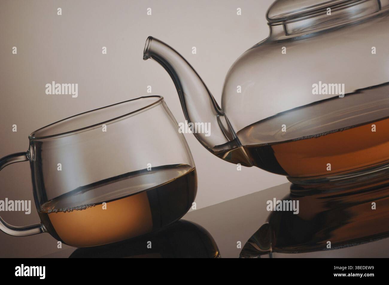 Teekanne aus transparentem Glas und Teetasse mit Reflexion Stockfoto