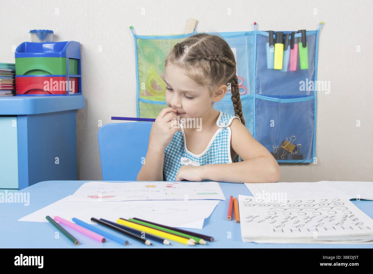 Fünfjähriges Mädchen zieht Bleistift in einem Notebook sitzen an einem Schreibtisch in der häuslichen Umgebung Stockfoto
