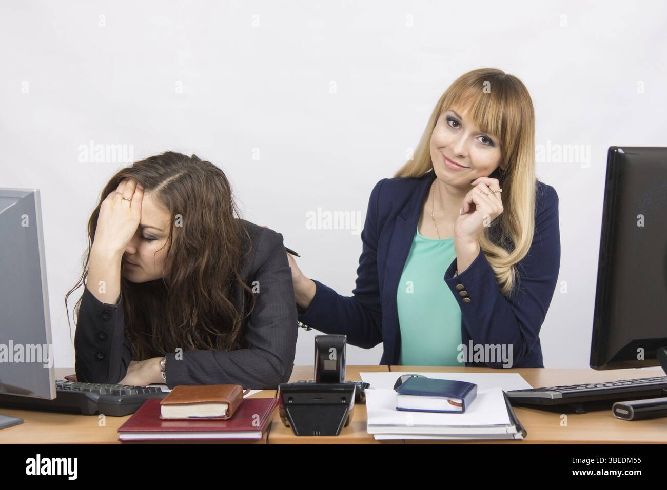 Zwei junge schöne Mädchen Kollegen am selben Schreibtisch im Büro Stockfoto
