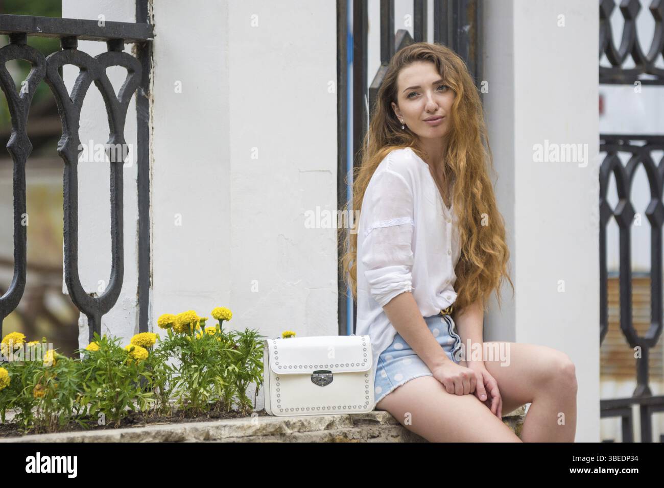 Ein junges Mädchen mit weißen Handtasche einer Dame kauerte in der Gasse auf der Straße Stockfoto