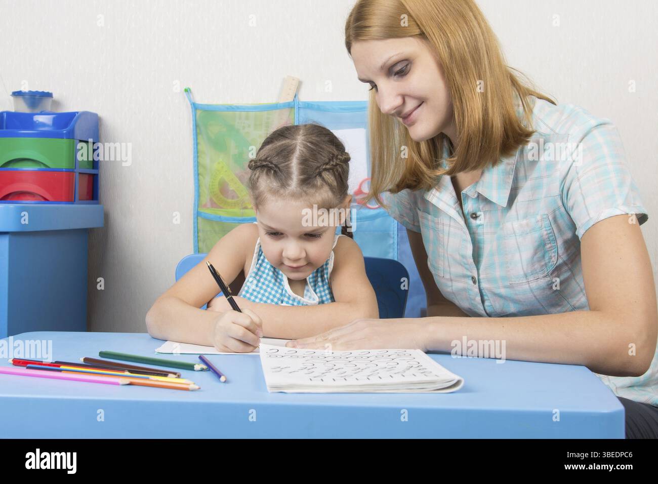 Eine fünfjähriges Mädchen engagiert sich Erwachsene junge schöne Mädchen sitzen am Tisch zu Hause Kinder Stockfoto