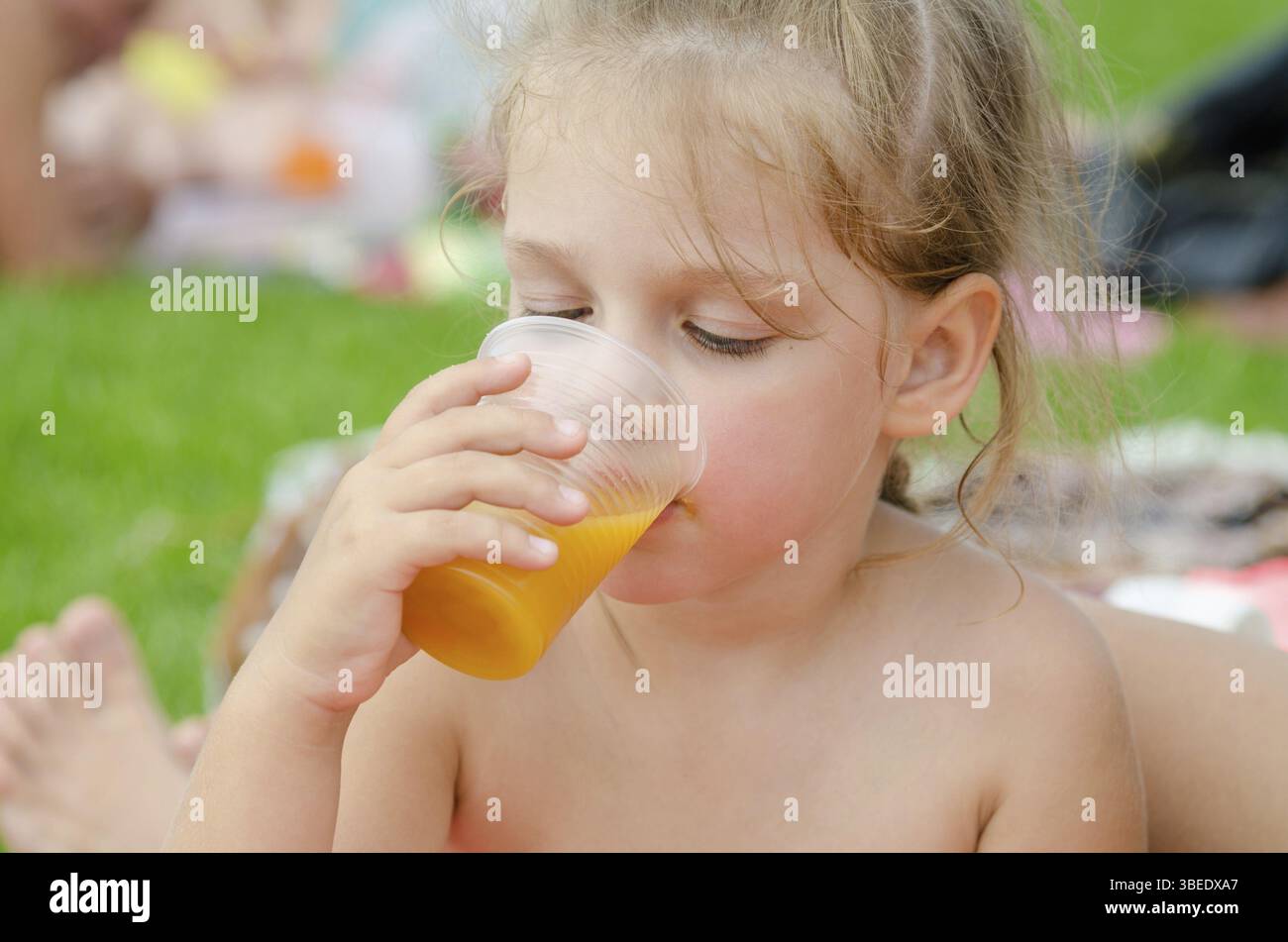 Mädchen trinken Fruchtsaft aus einem Einweg-Plastikbecher Stockfoto