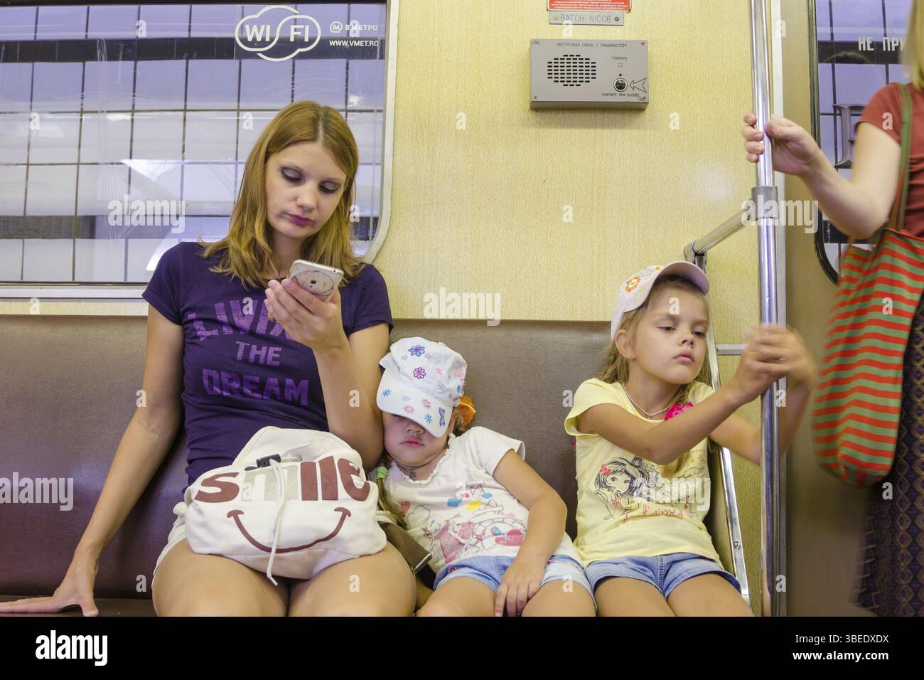 Moskau, Russland - 10. August 2015: Die Situation im Zug der Moskauer U-Bahn, die Mutter schaut auf das Telefon, die jüngste Tochter schläft, die Stockfoto