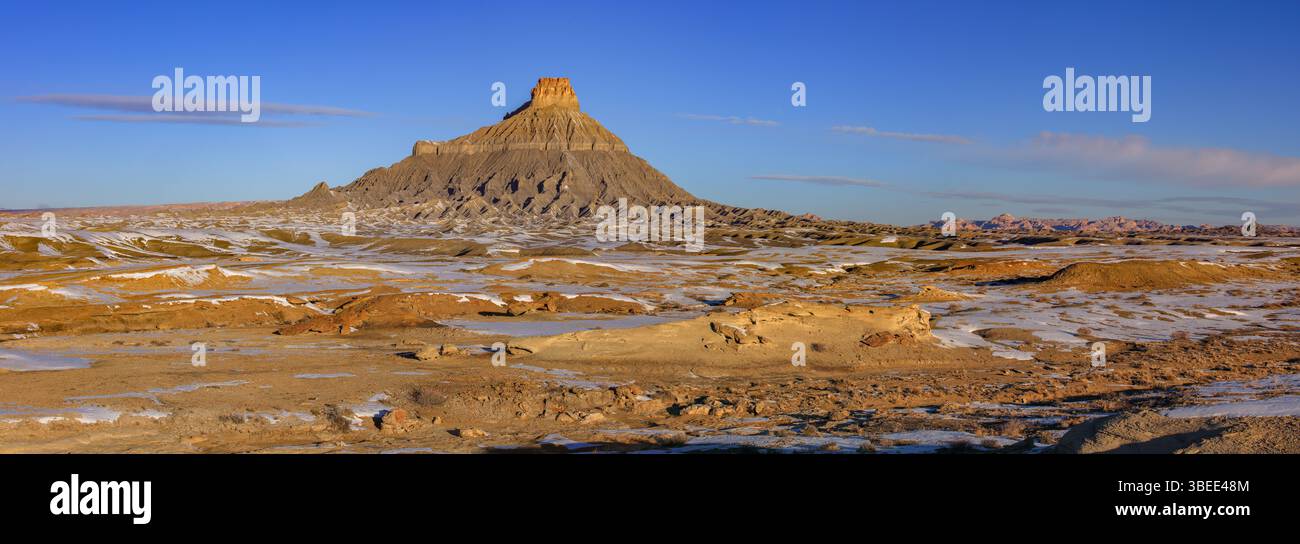 Der atemberaubende Factory Butte erhebt sich über den seltenen schneebedeckten Wüstenbadlands in der Nähe von Hanksville, Utah. Stockfoto