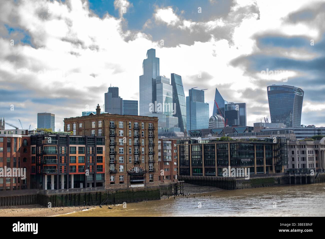 Das Bild zeigt Londons Skyline mit modernen Wolkenkratzern, die über älteren Gebäuden am Fluss ragen. Stockfoto