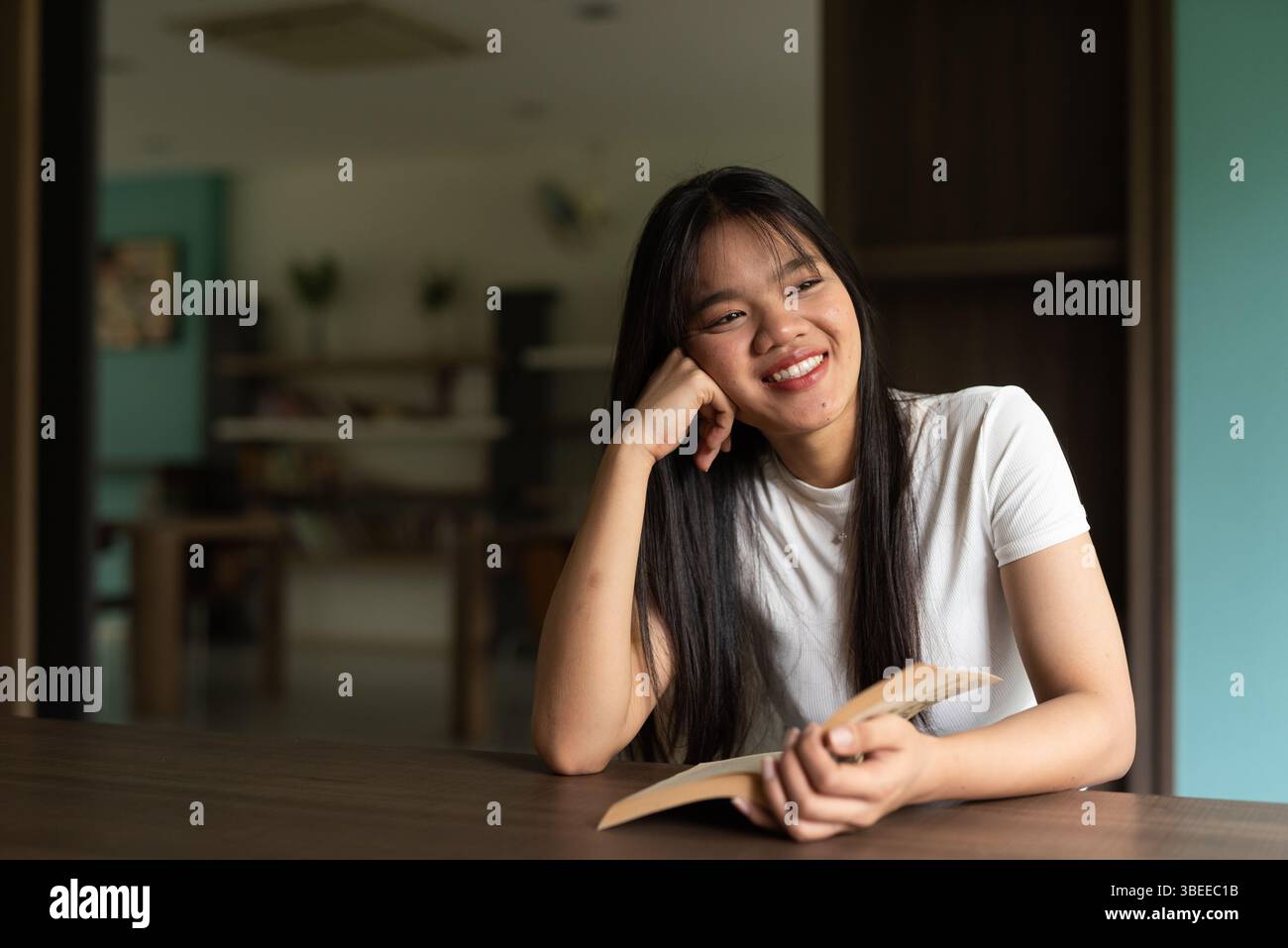 Junge, schöne asiatische Frau, die Buch in der Bibliothek liest Stockfoto