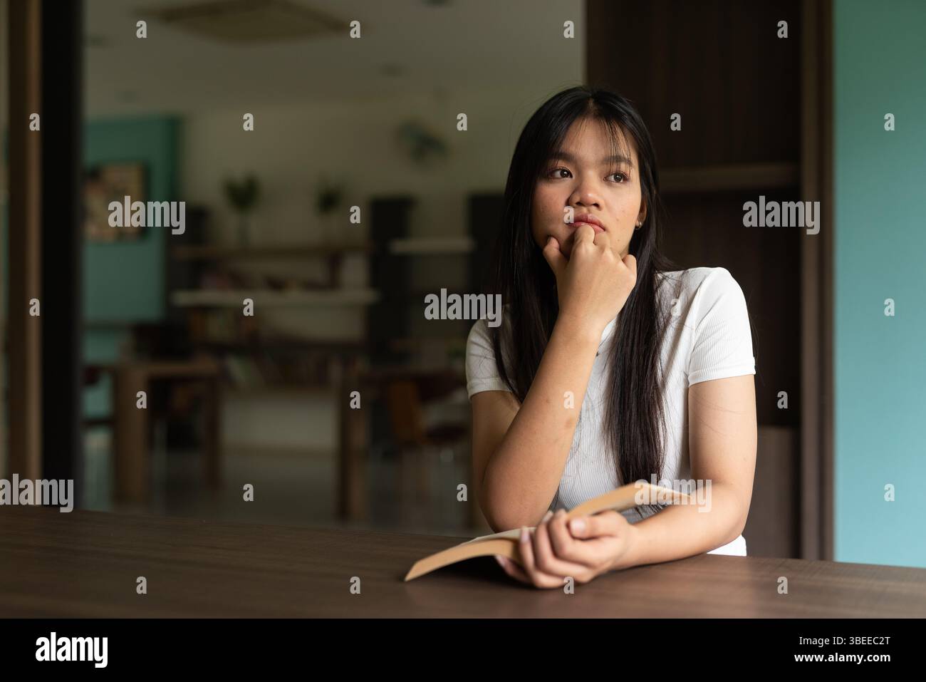 Junge, schöne asiatische Frau, die Buch in der Bibliothek liest Stockfoto