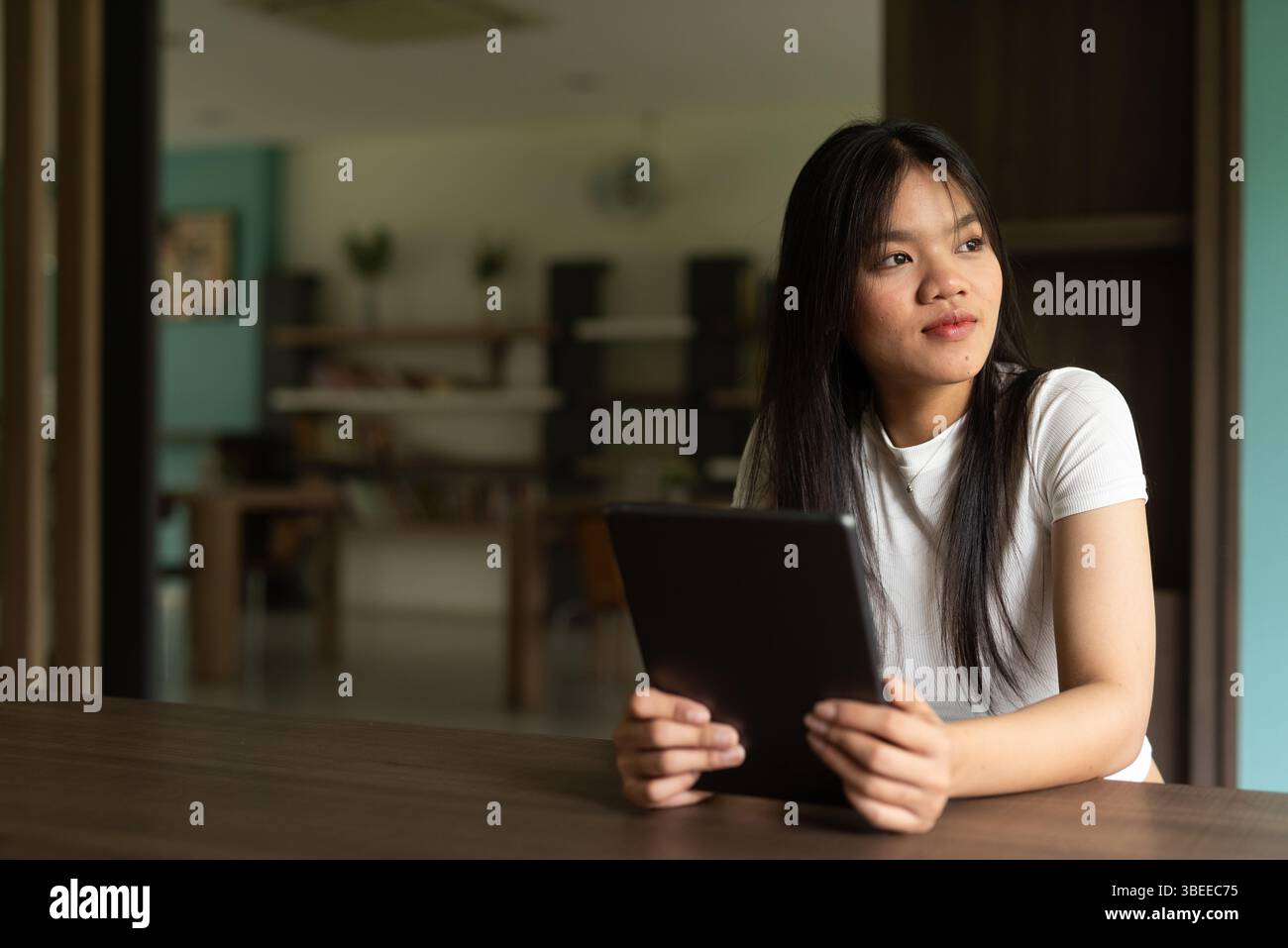 Junge asiatische Studentin, die ein digitales Tablet in der Bibliothek benutzt Stockfoto