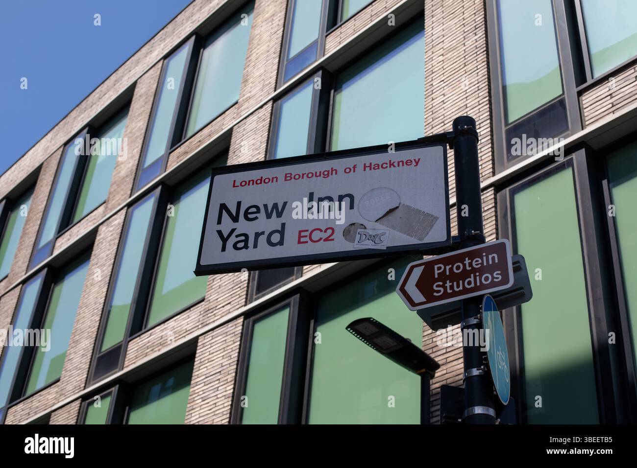 Schilder für New Inn Yard und Protein Studios in Hackney, London, vor einem modernen Gebäude. Stockfoto