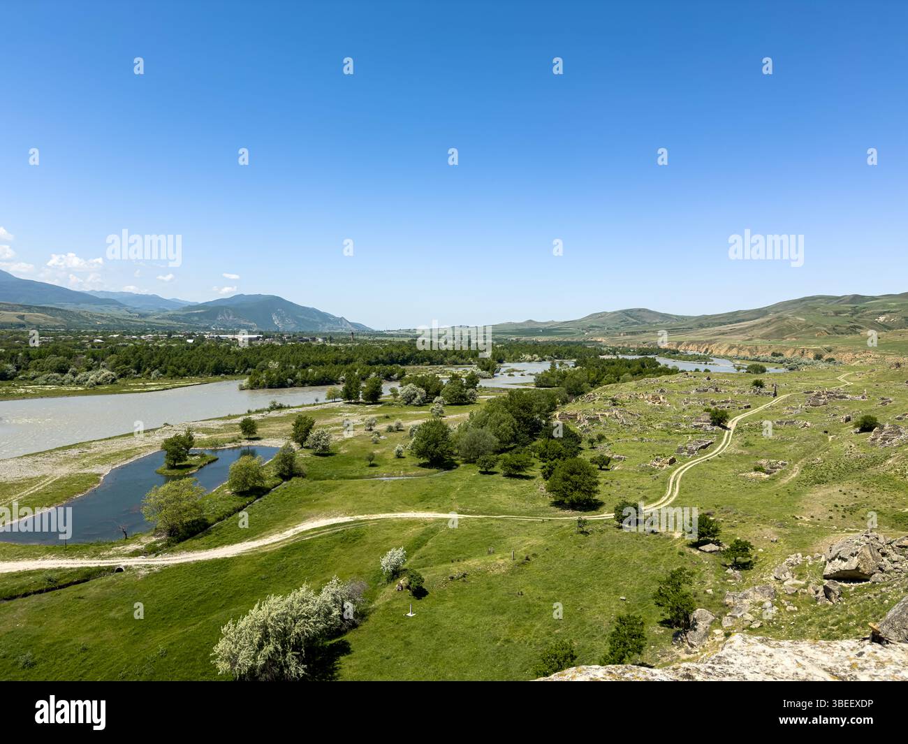 Malerischer Panoramablick auf das Flusstal mit grünen Feldern, Hügeln und fernen Bergen unter klarem blauem Himmel, Weitwinkel, Tageslicht. Keine Personen. Stockfoto