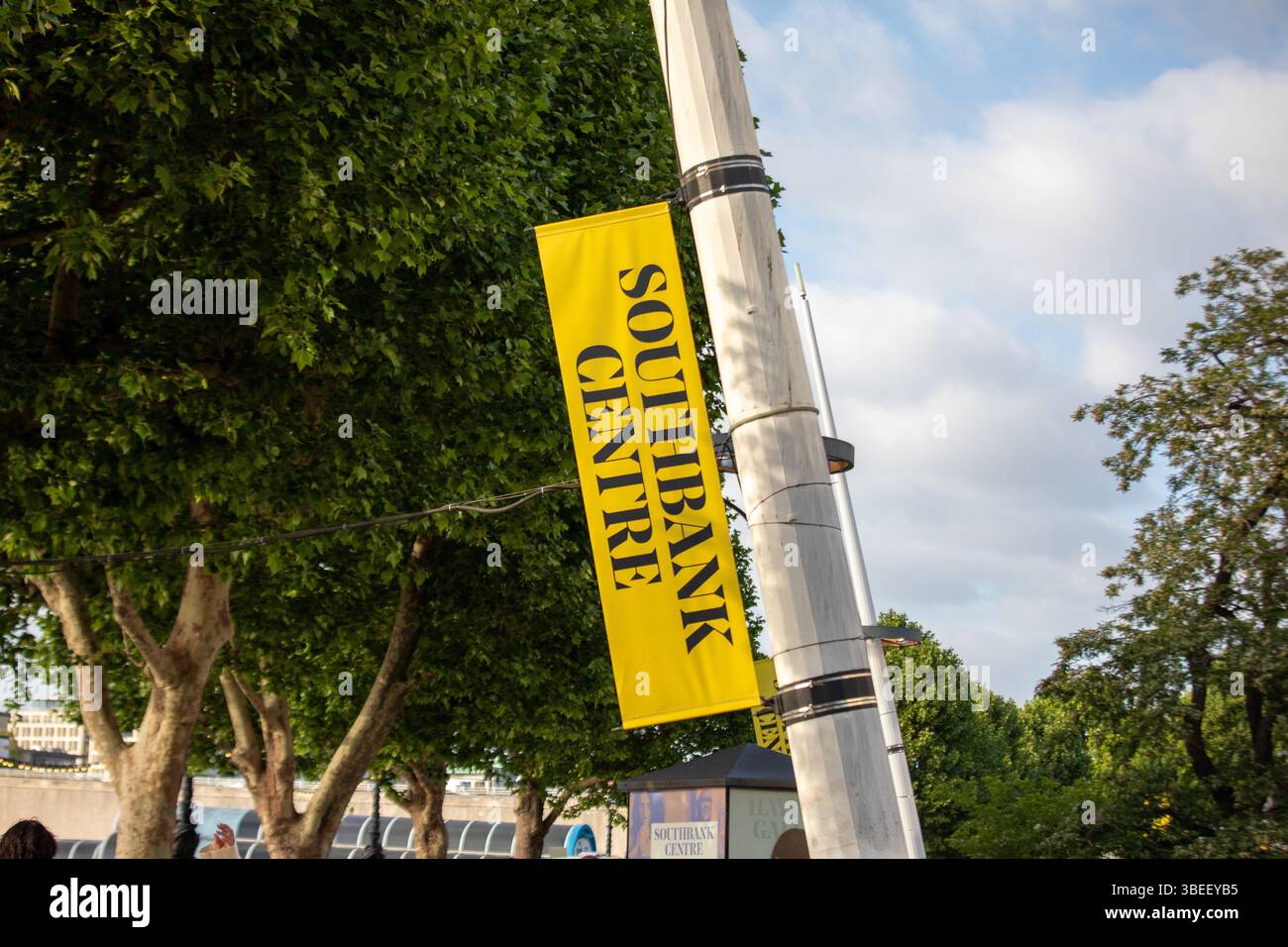 Ein gelbes Schild am Southbank Centre an einem Stab, umgeben von üppig grünen Bäumen in London. Stockfoto