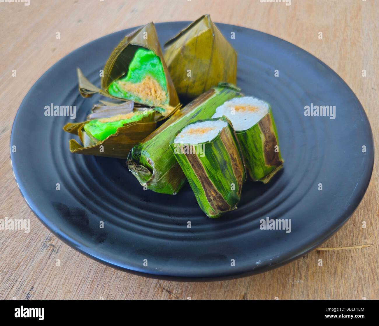 Traditionelles indonesisches Dessert, traditioneller indonesischer Kuchen, Lemper wird aus klebrigem Reis hergestellt und gefüllt mit gehacktem Hühnchen, Mendut- oder Bugis-Kuchen oder Koci-Kuchen mit Dreiecksform wie Pyramide, hergestellt aus klebrigem Reis und gefüllt mit Becherbohnen, Zucker, geriebenem Kakao, beide in Bananenblätter gewickelt Stockfoto