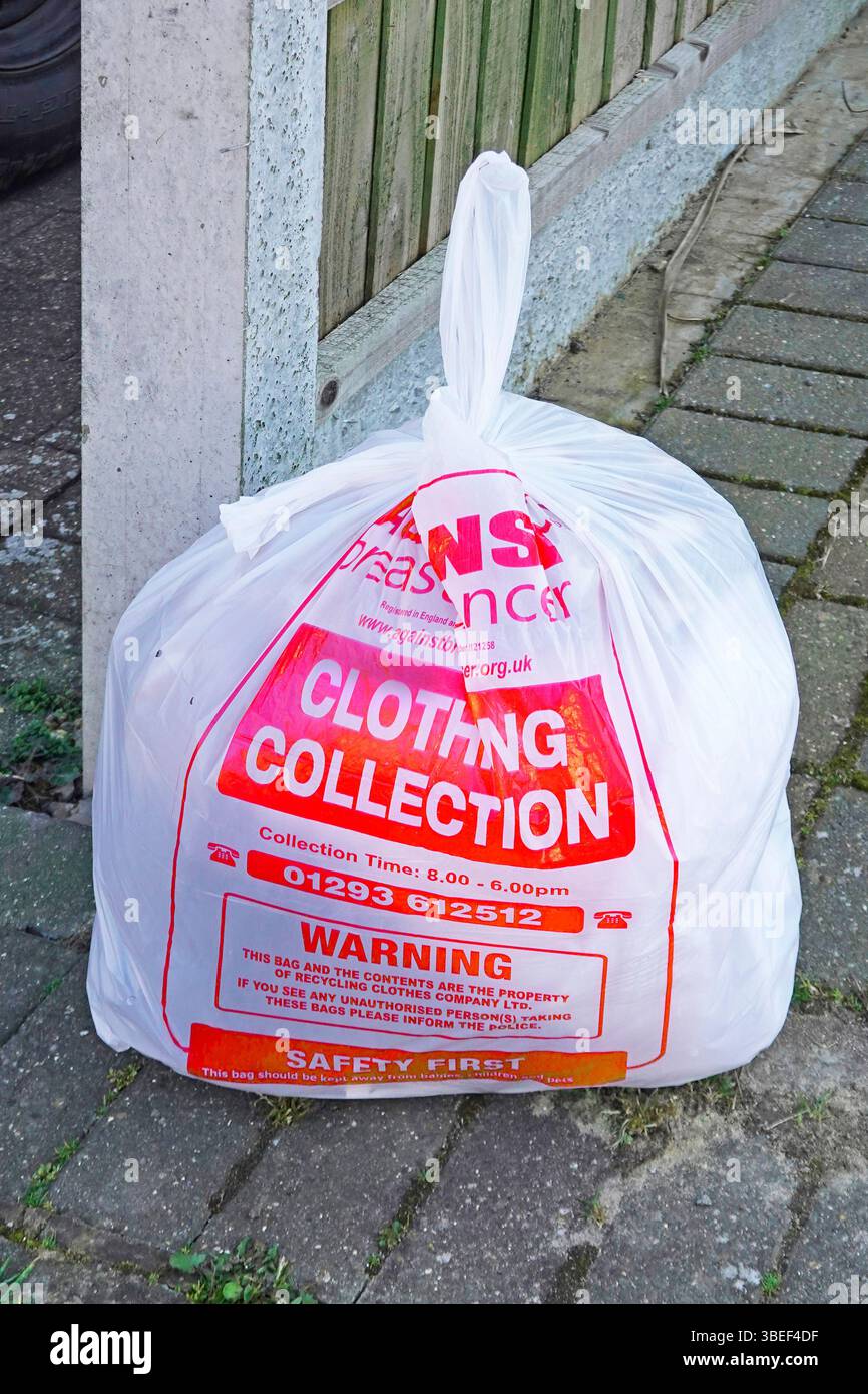 Rote und weiße Wohltätigkeitssacktüte recyceln, die über ein Bekleidungsgeschäft auf öffentlichem Bürgersteig für die Abholung im Van Essex UK zur Verfügung steht Stockfoto