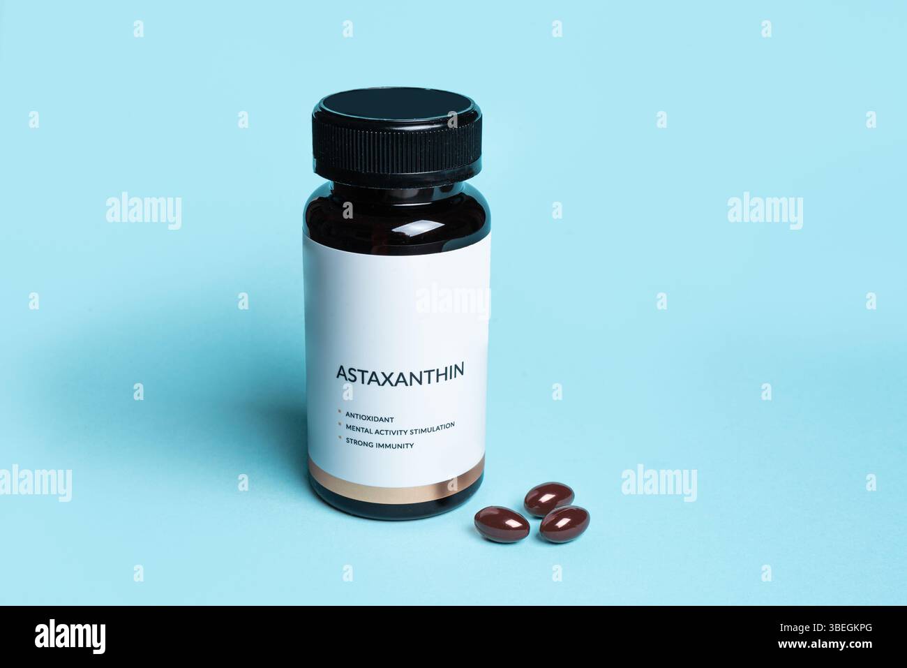 Astaxanthin-Präparat in Flasche mit leerem Etikett auf blauem Hintergrund, Kopierraum. Gesunder Lebensstil, Antioxidans-Diät-Ergänzung. Stockfoto