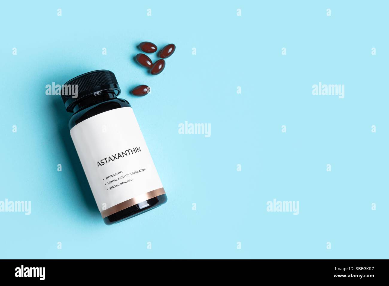 Astaxanthin-Präparat in Flasche mit leerem Etikett auf blauem Hintergrund, Kopierraum. Gesunder Lebensstil, Antioxidans-Diät-Ergänzung. Stockfoto
