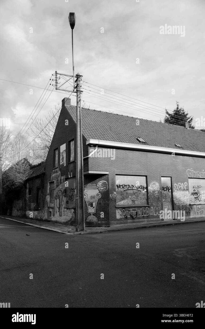 Städtischer Verfall in Schwarz-weiß, das ein verlassenes Gebäude mit Graffiti in einer ruhigen Straße zeigt Stockfoto