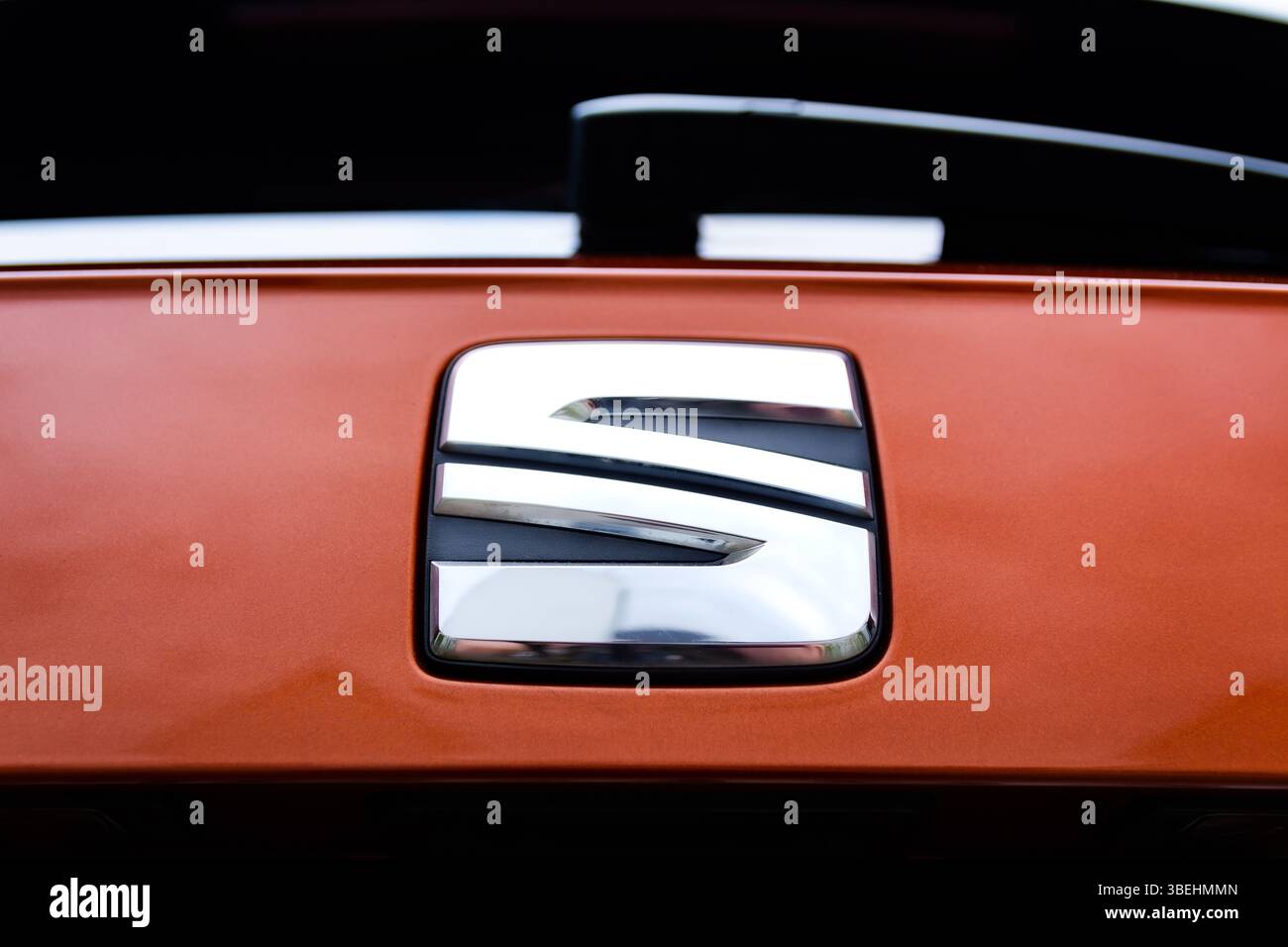 Nahaufnahme des verchromten Autoemblems auf orangefarbener Karosserie Stockfoto