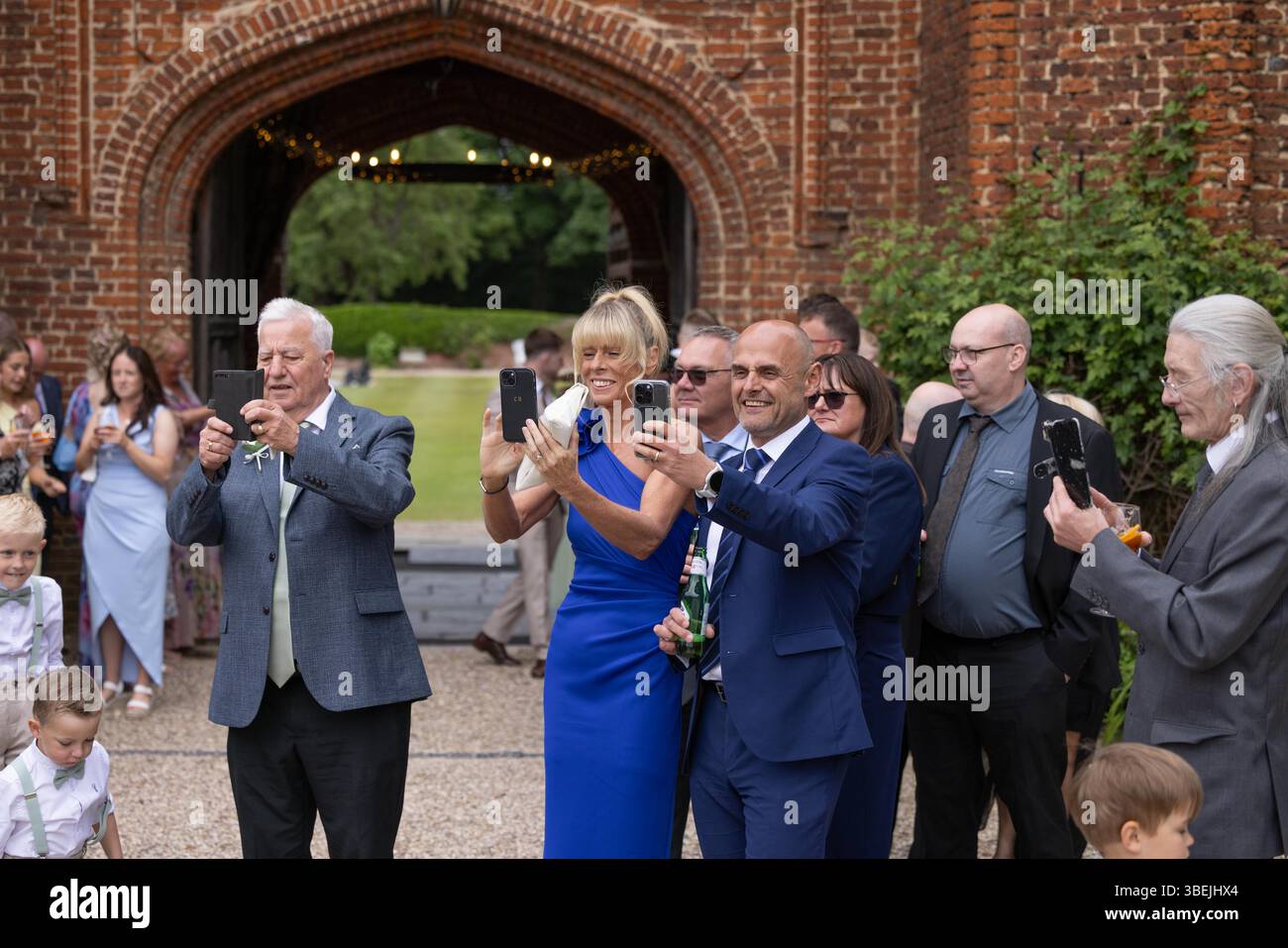 Gast bei der Hochzeit, der Fotos mit dem Mobiltelefon der Braut und des Bräutigams macht. Stockfoto