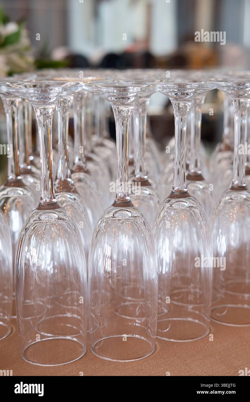 Viele umgedrehte Sektflöten, die ordentlich auf einem braunen Stoff angeordnet sind, elegante, schmalstielige Gläser, die normalerweise zum Servieren von Sekt verwendet werden Stockfoto