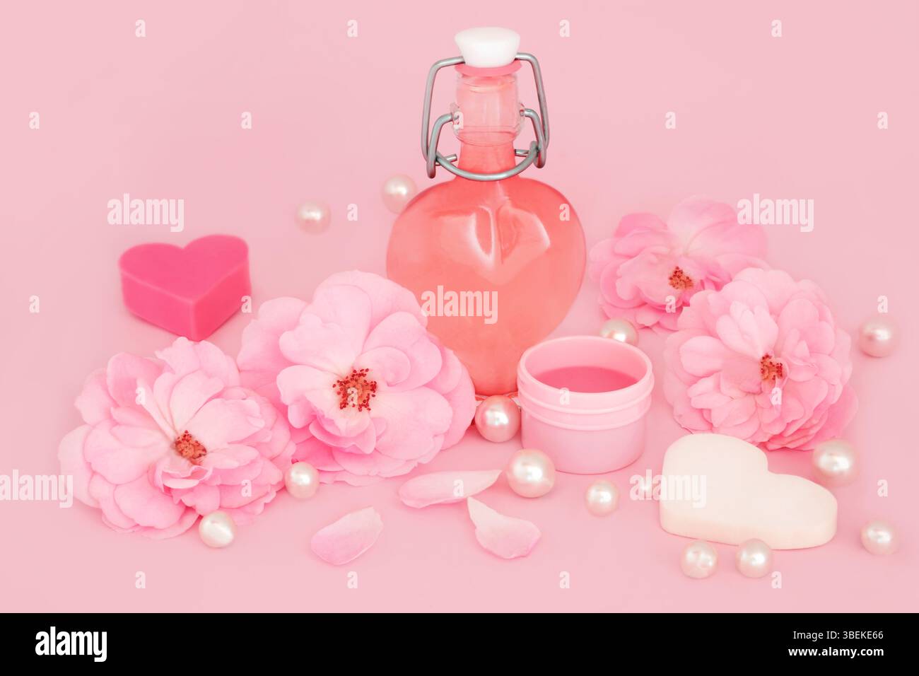 Romantische Rose Flower Spa feminine Schönheitsbehandlungsprodukte zur Hautpflege Heilung auf Rosa mit Perlen mit Herzform Flasche. Stockfoto